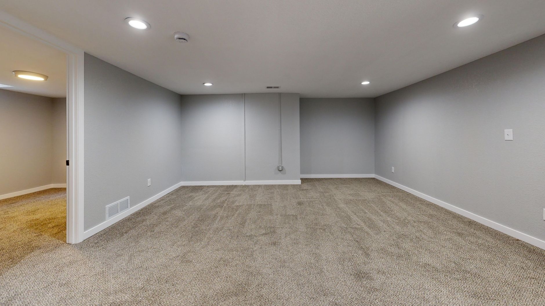 Empty finished basement room with carpet and painted gray walls