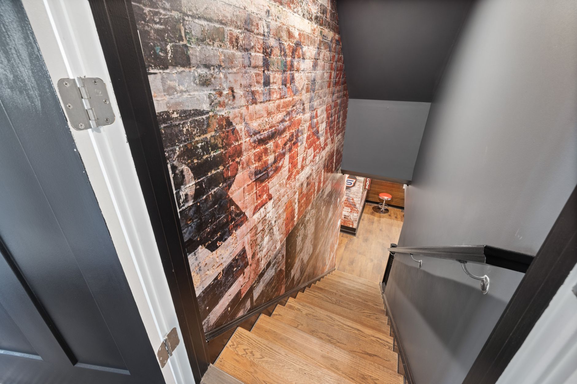 Finished basement stairway beside an exposed painted brick wall