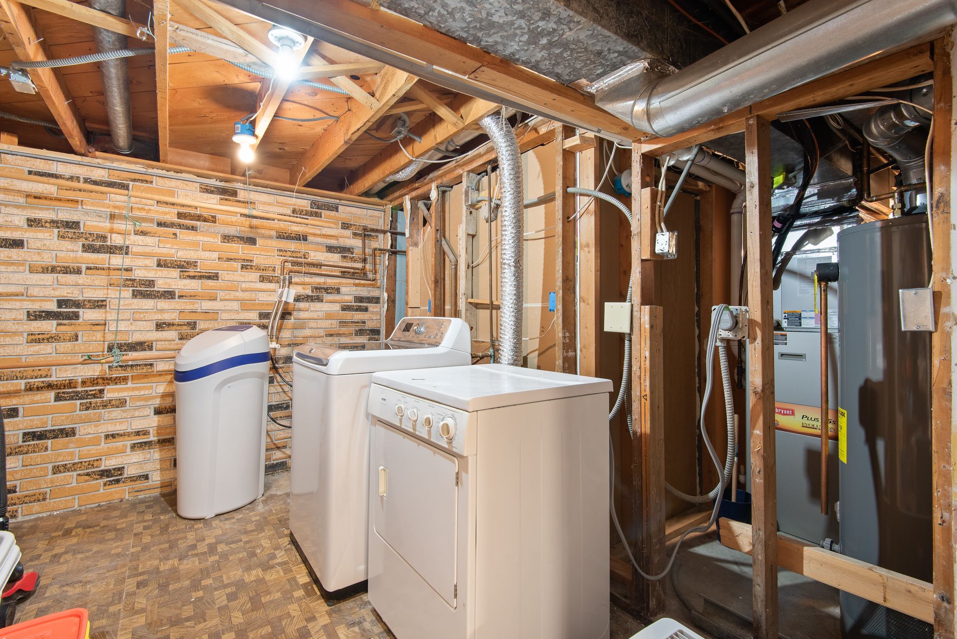 Unfinished basement utility area with furnace, water heater, and exposed floor joists