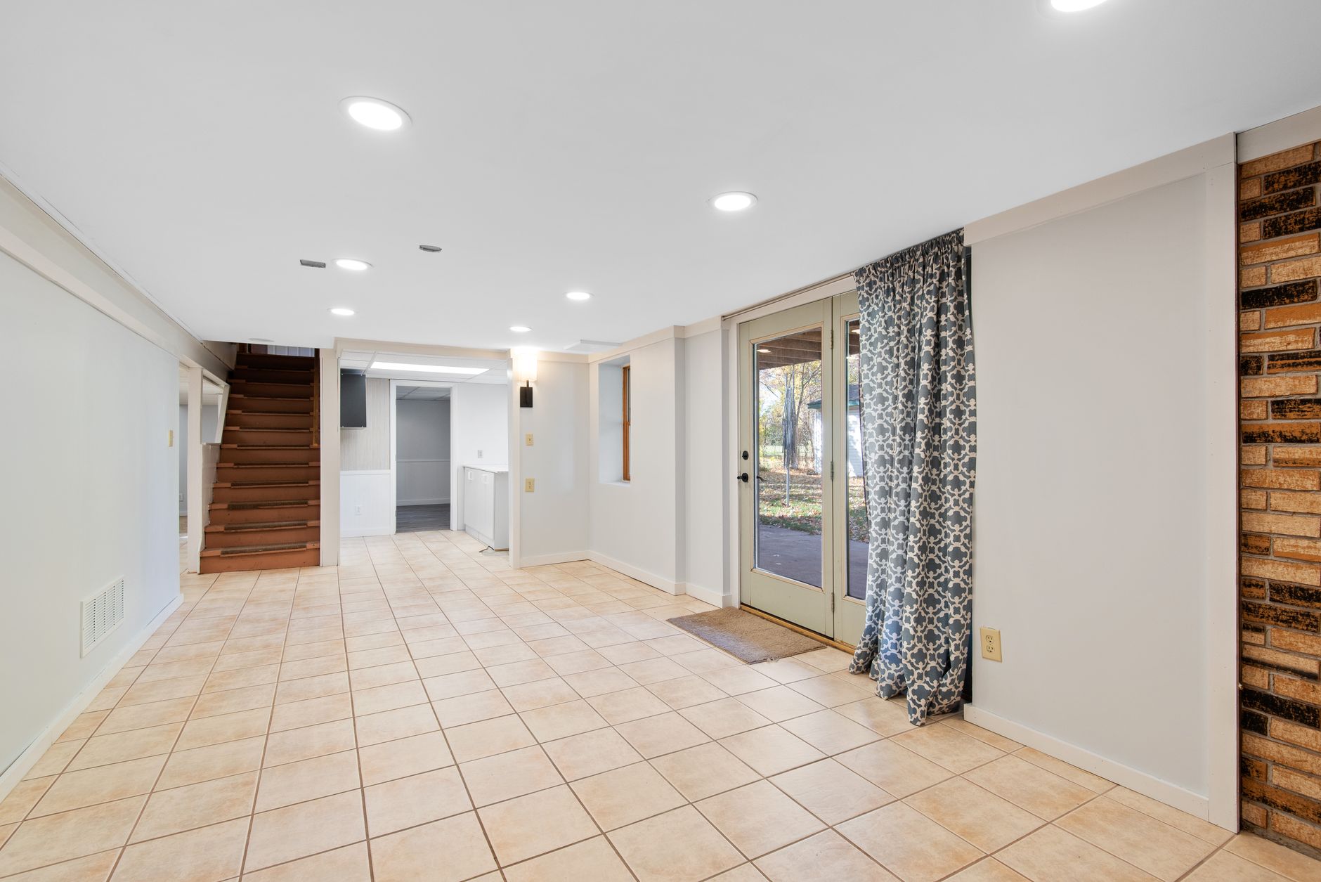 Finished basement with tile flooring, stairs, and glass walkout doors