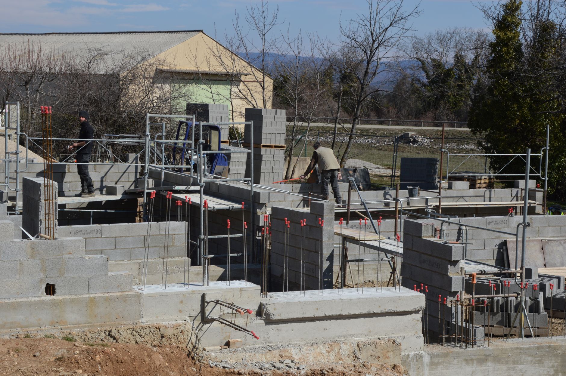 Masons laying concrete block foundation walls on a poured footing