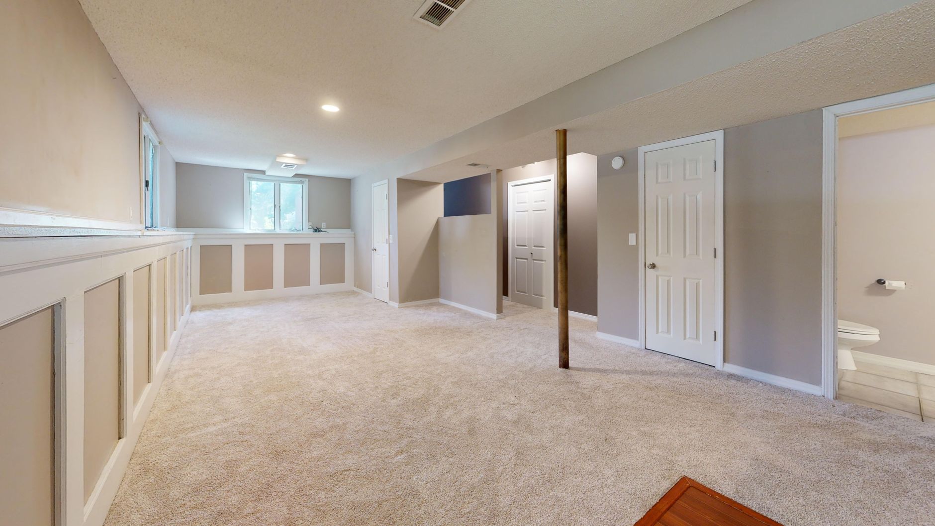 Finished basement living area with carpeted floor and recessed lighting