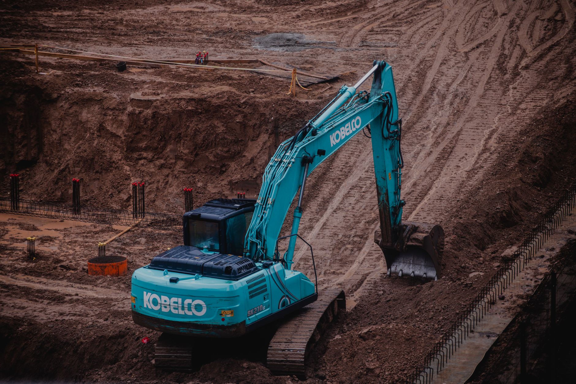 Excavator working in a deep foundation excavation beside a poured footing