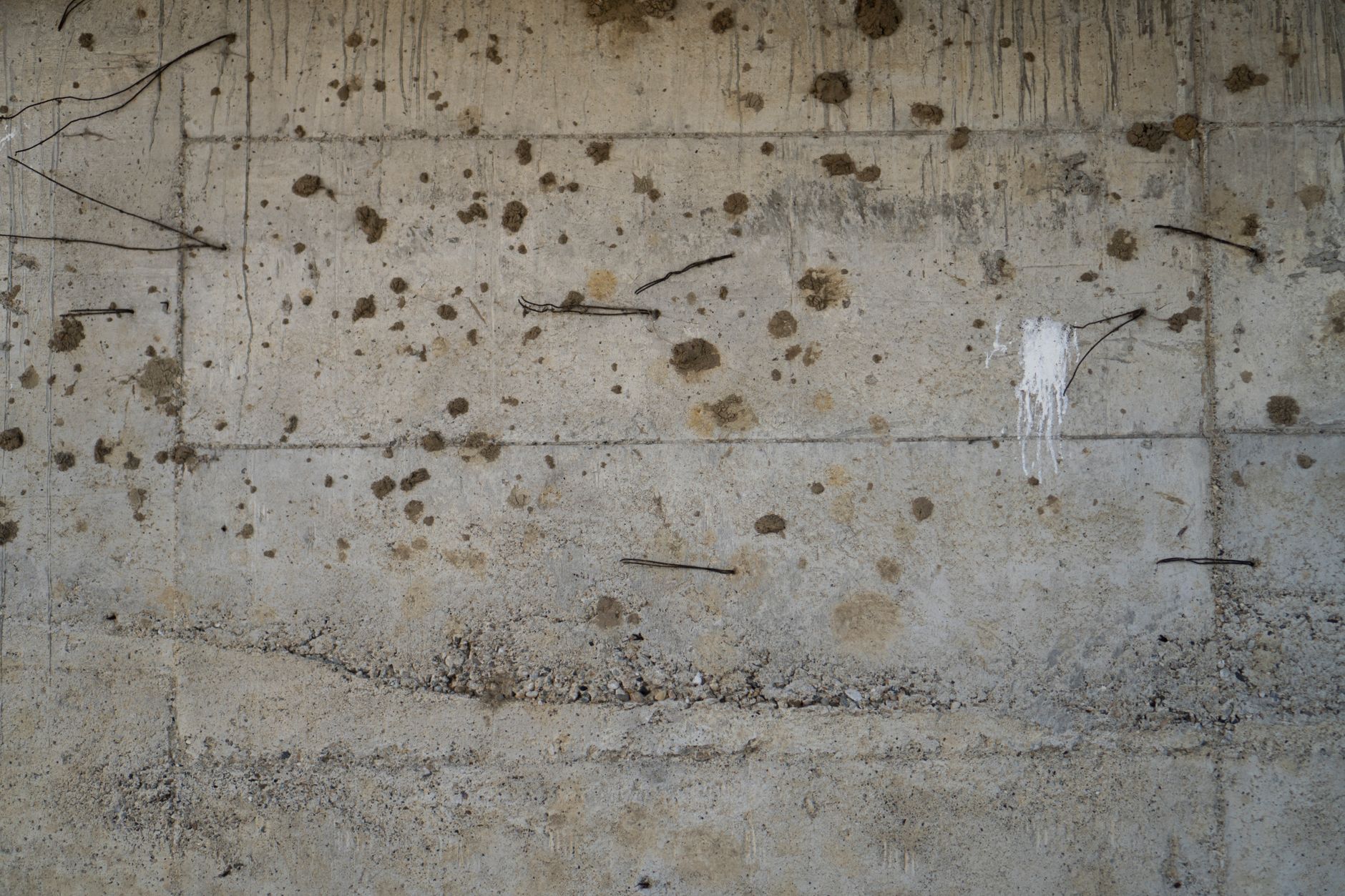 Poured concrete foundation wall showing form-tie wires and surface pitting